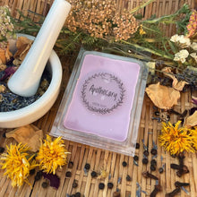 Load image into Gallery viewer, Purple wax melt with 'Apothecary' label on a woven surface with herbs and flowers.