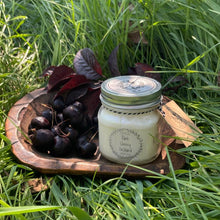 Load image into Gallery viewer, &quot;Dark Cherry Orchard&quot; candle on a wooden plate with cherries in grass